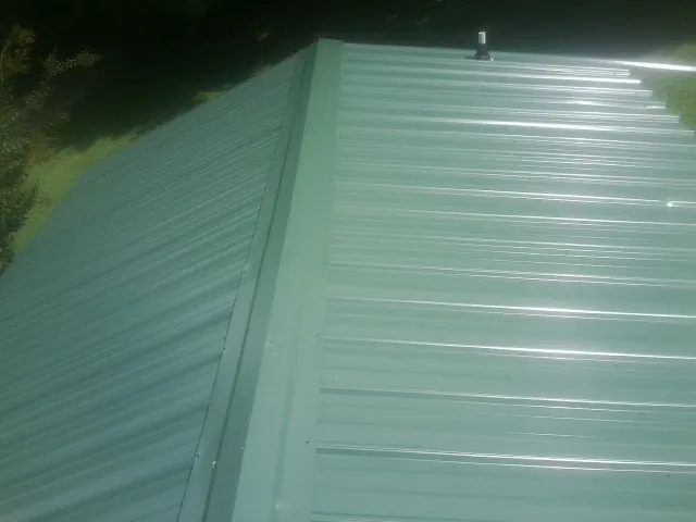 New green metal panels meeting at the ridge of a roof — Flat Roof Repair work by our crew in Selkirk