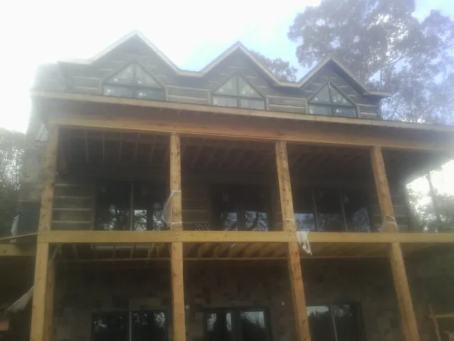 Dormers and porch framing on a large log home under construction — Roof Coating work by our crew in Selkirk