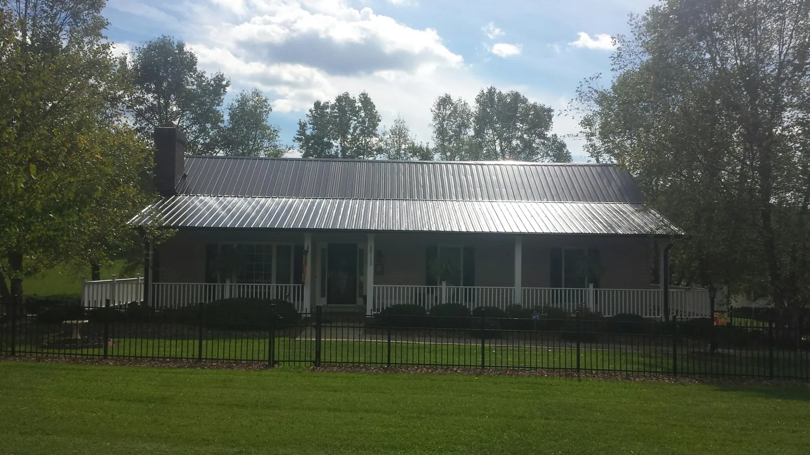 Gray metal roof on a brick ranch with a full width front porch — Gutter Guard Installation work by our crew in Selkirk