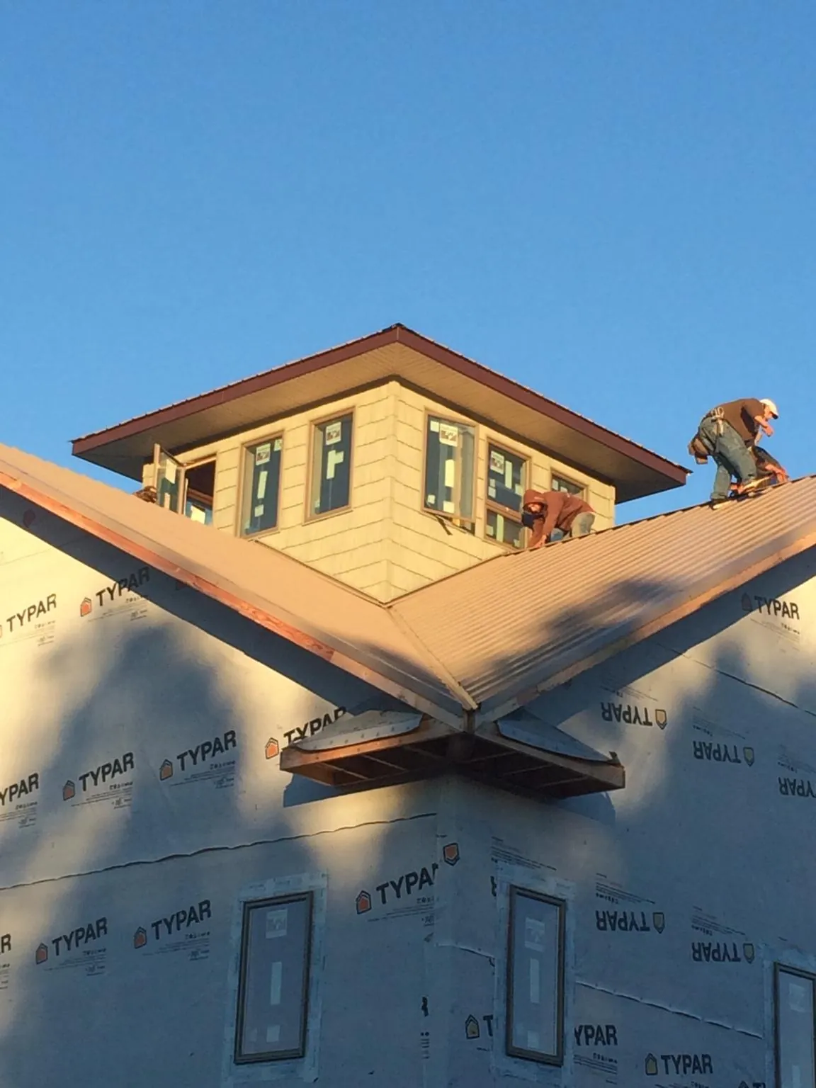 Roofers working around a rooftop cupola on a new metal roof at sunset — Roof Waterproofing in Selkirk by Roofing Brothers